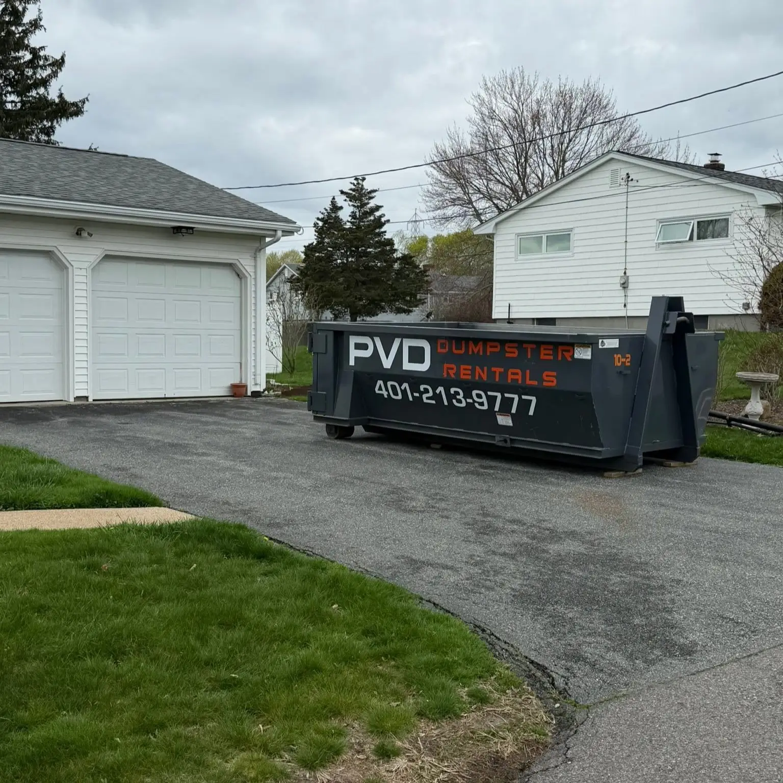 10 yard dumpster set beside a garage door on a residential driveway