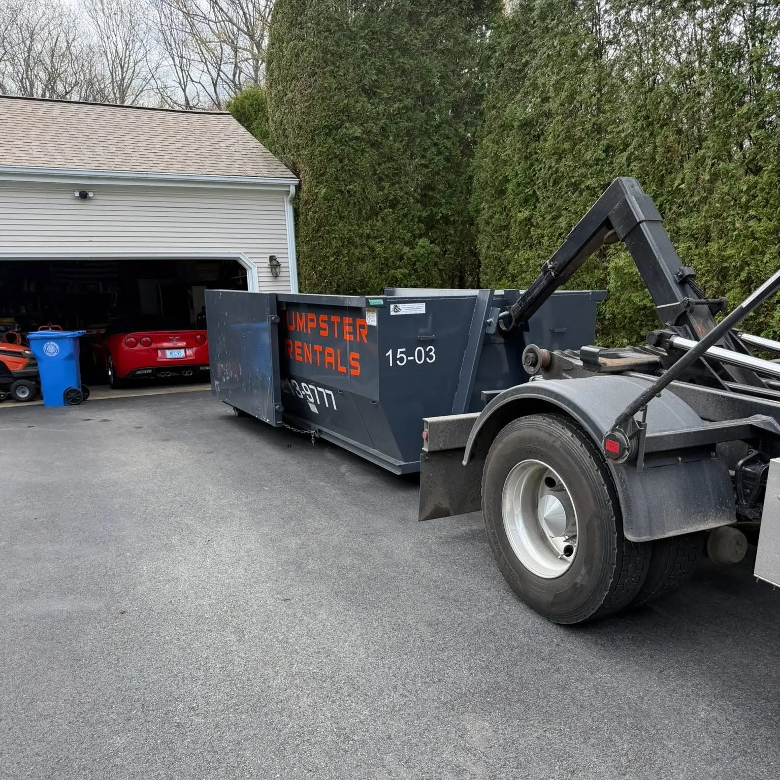 15 yard dumpster being picked up from a residential driveway