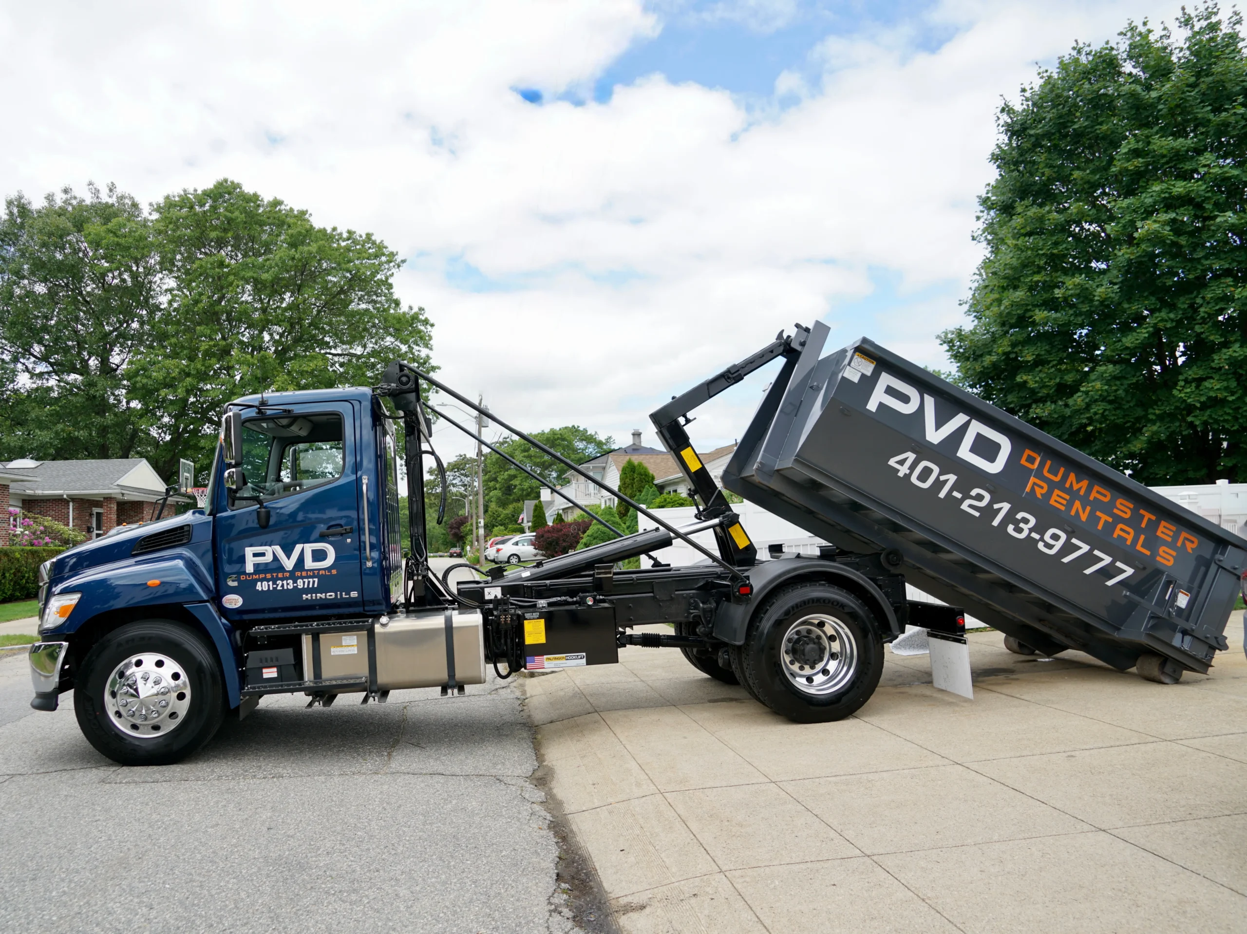 Hooklift raising a dumpster container onto the truck